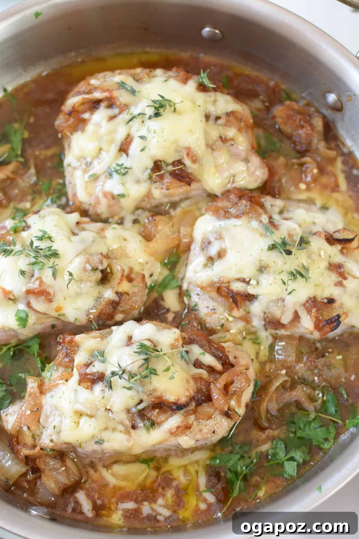 Sizzling French Onion Pork Chops in a rustic cast-iron skillet, topped with melted Gruyère and golden caramelized onions.