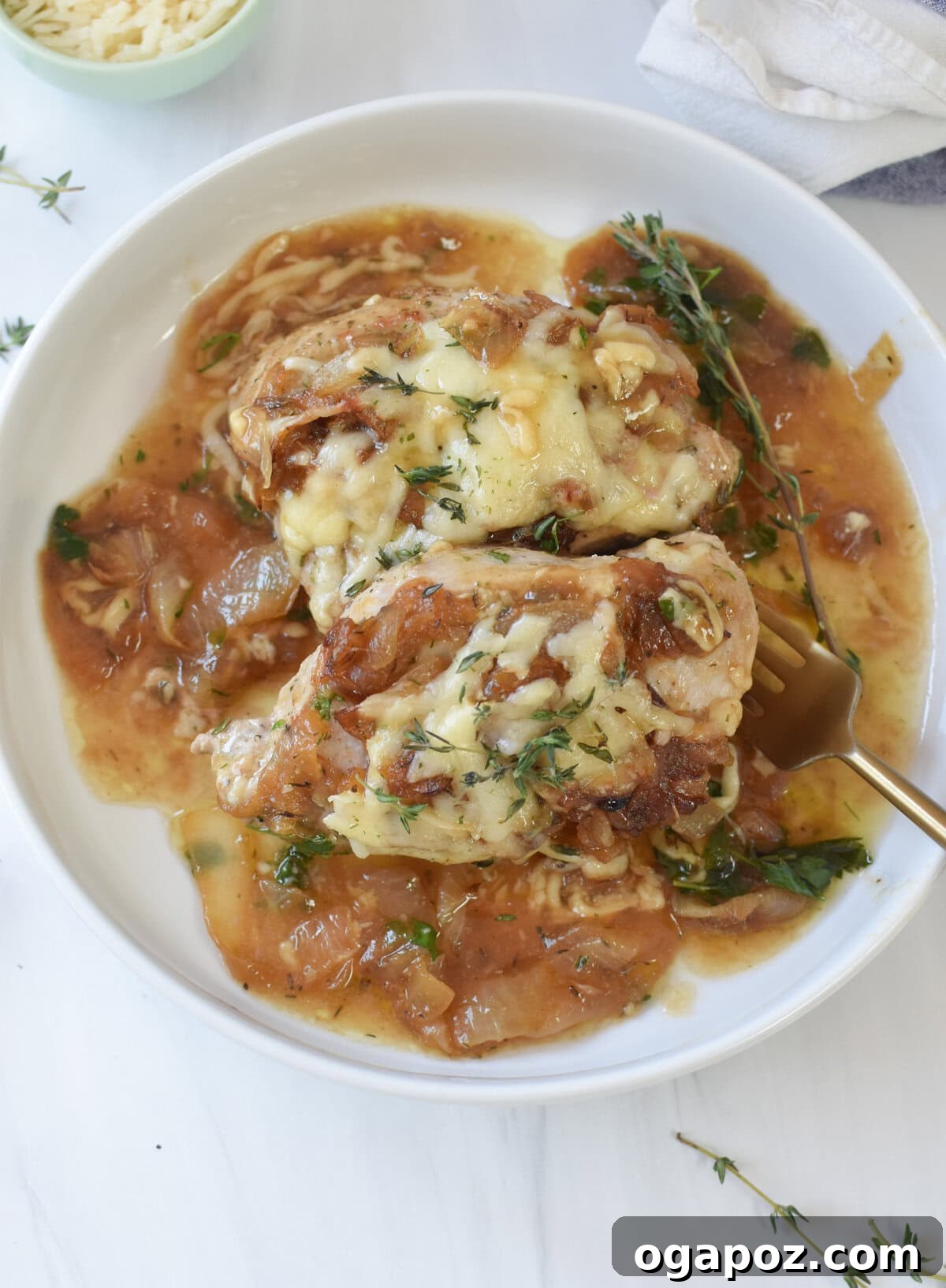 A serving of French Onion Pork Chops, generously topped with melted cheese and fresh herbs, presented in a shallow bowl.
