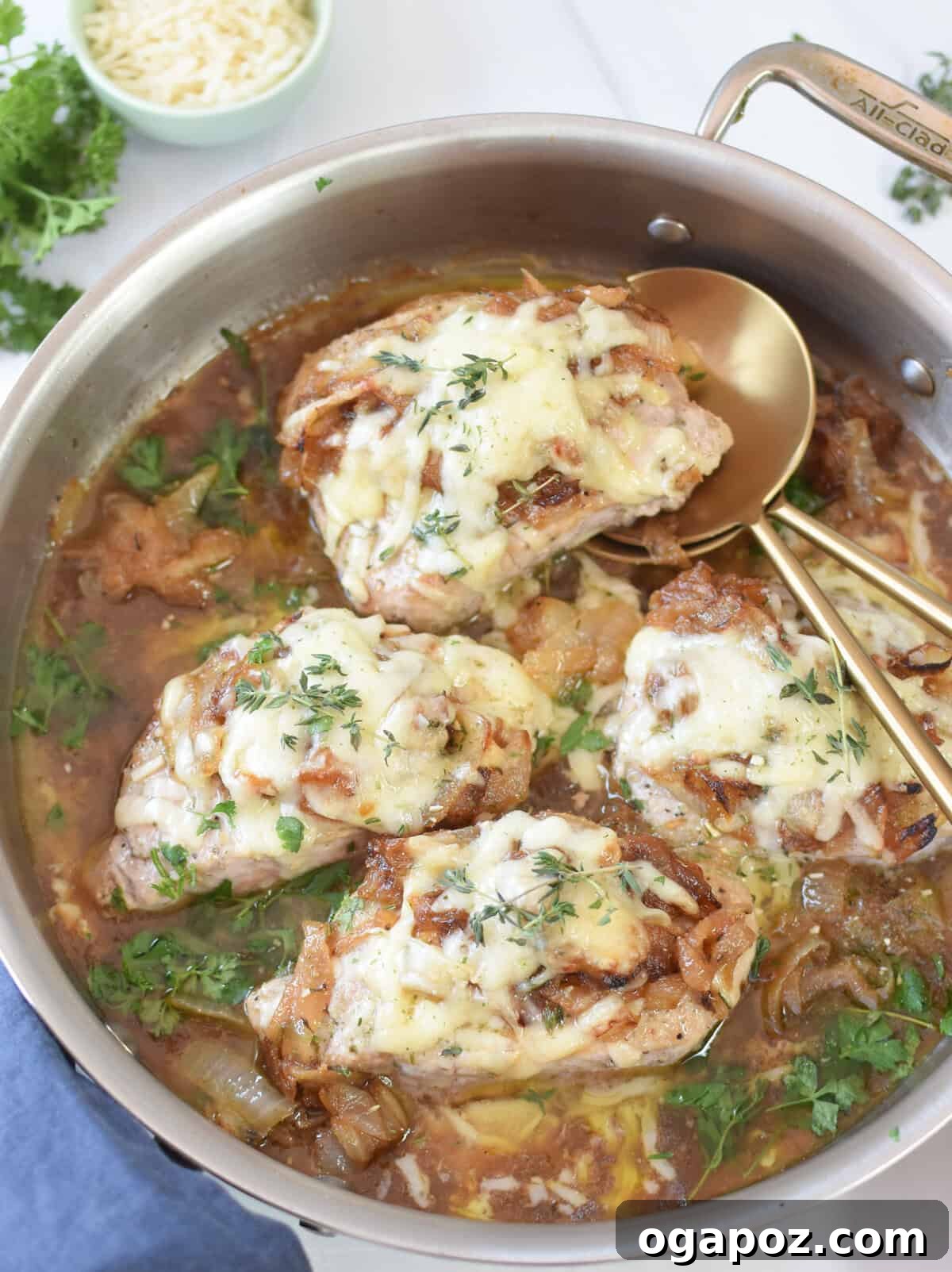 French Onion Pork Chops plated with golden serving spoons, showcasing the rich sauce and melted cheese.