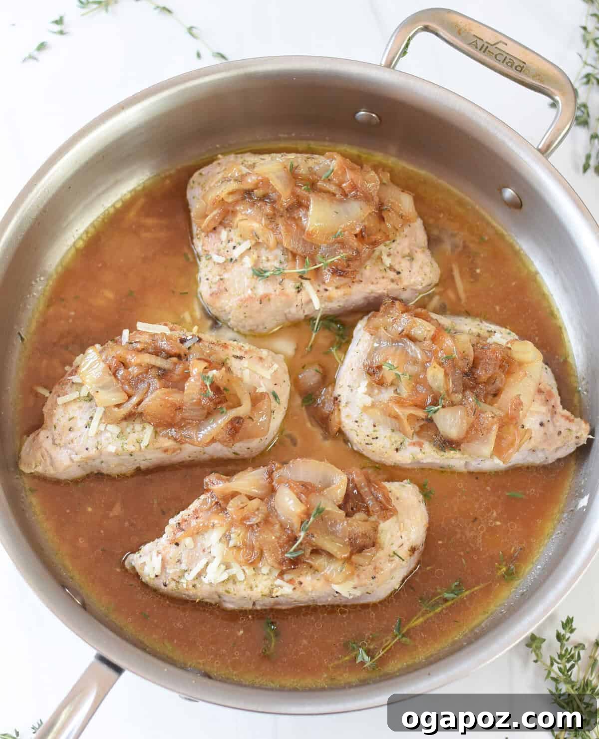 French Onion Pork Chops baking in a skillet, with melted Gruyère cheese bubbling over the caramelized onions.