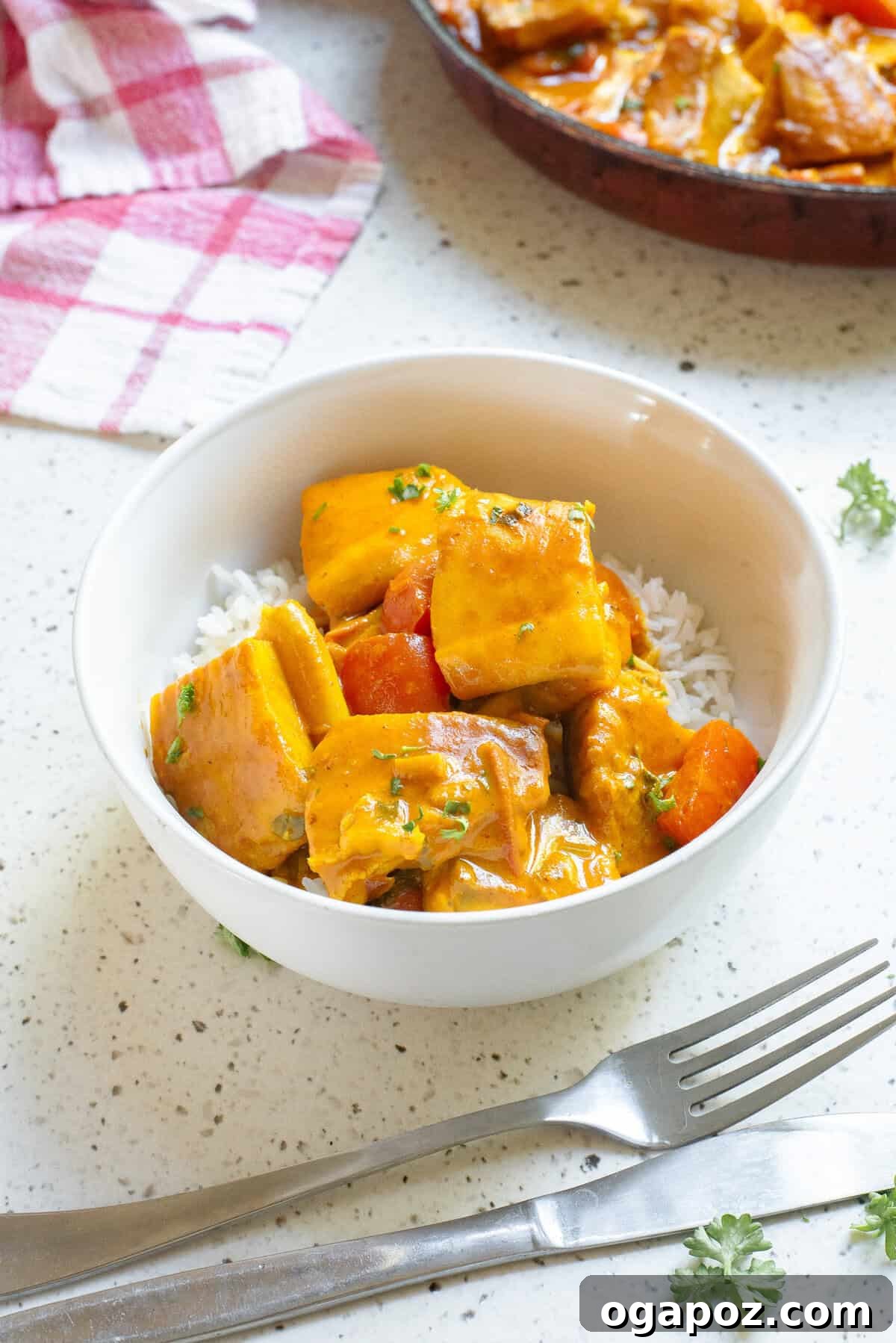 Close-up of a perfectly cooked coconut fish curry in a deep skillet, garnished with fresh herbs.