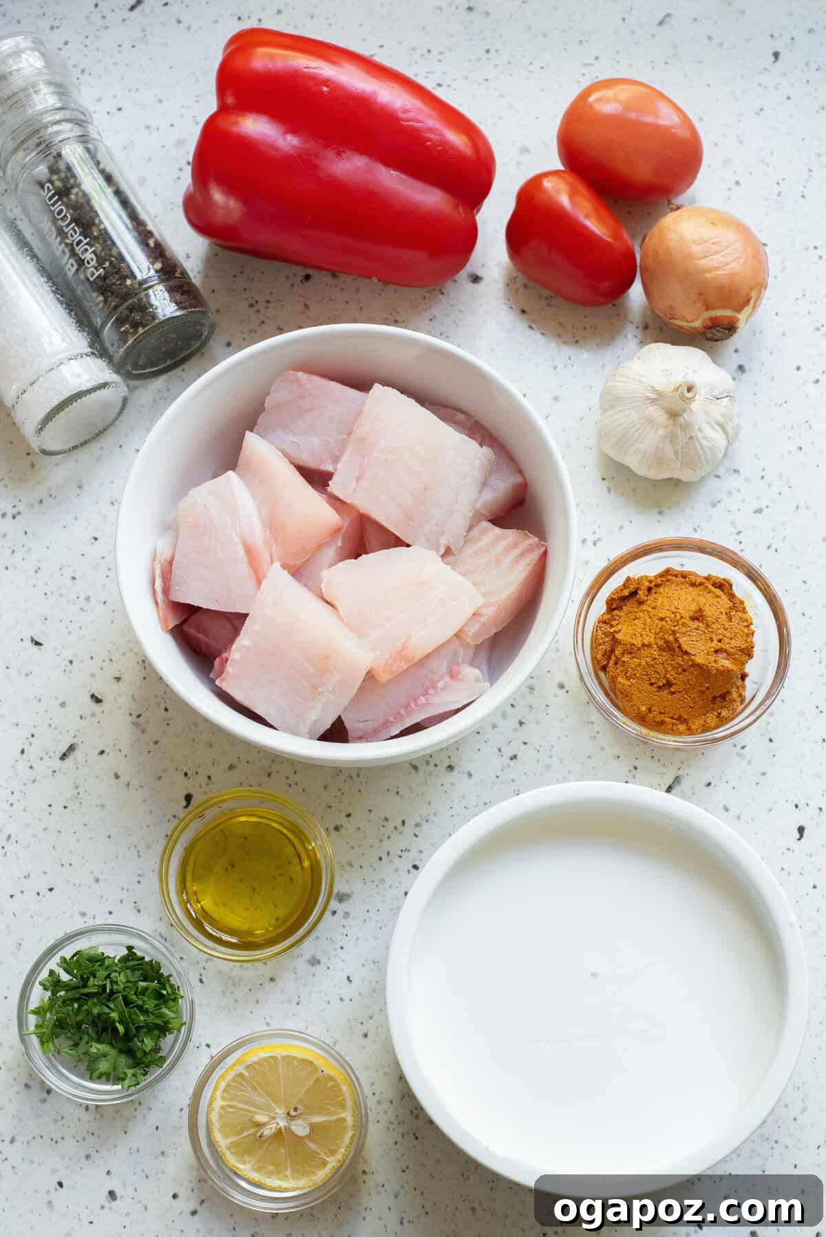 A selection of fresh ingredients for Coconut Fish Curry laid out on a table, including fish fillets, vegetables, spices, and coconut milk.