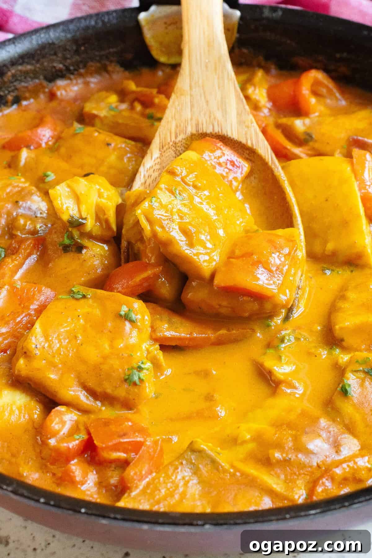 A delicious Coconut Fish Curry simmering gently in a black skillet on the stove.