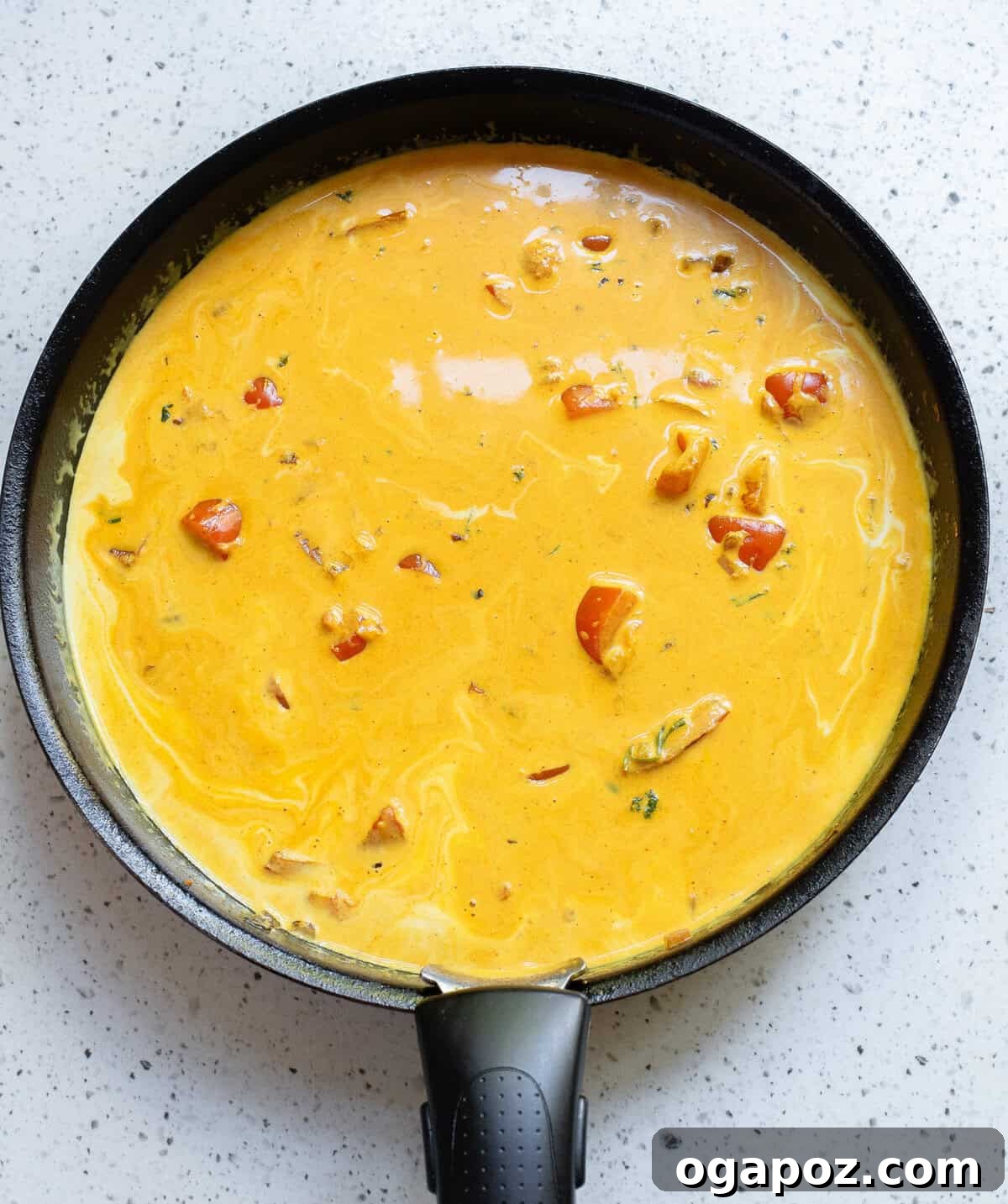 The rich and creamy coconut fish curry simmering gently in a black skillet, with the fish pieces perfectly cooked.