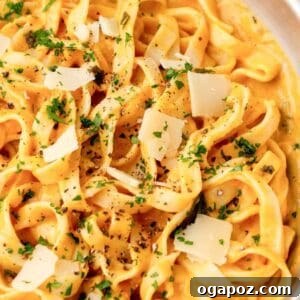 Velvety Pumpkin Pasta Sauce 2 A bowl of creamy pumpkin pasta garnished with fresh sage leaves and grated parmesan cheese.