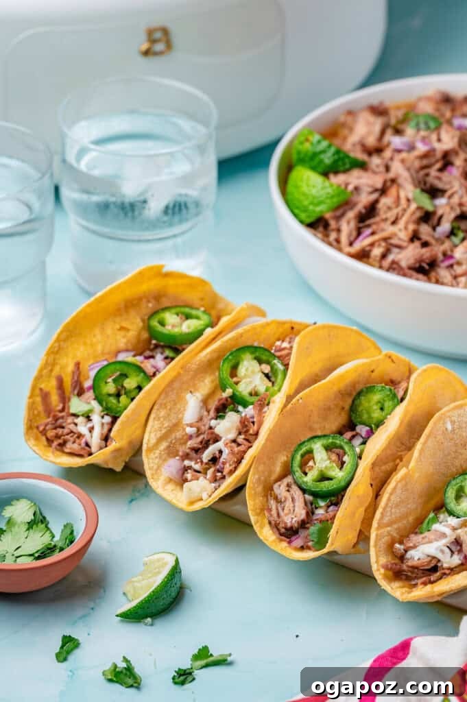 Tender Slow Cooker Pulled Pork Tacos 6 Three beautifully assembled Slow Cooker Pulled Pork Tacos on a rustic wooden board, garnished with fresh cilantro and cotija cheese