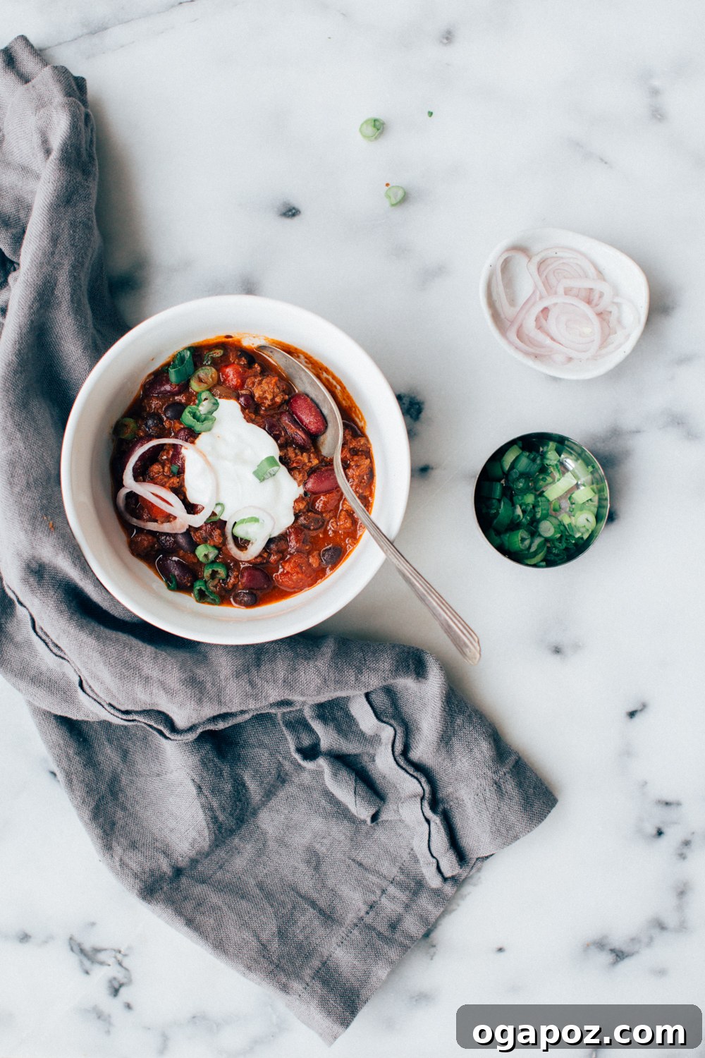 Rich and Flavorful Chili Con Carne 9 A close-up of a bowl of chili con carne topped generously with shredded cheddar cheese, a dollop of sour cream, and fresh cilantro.