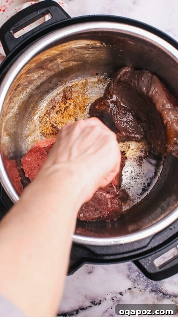 Hearty Instant Pot Beef and Barley Soup 5 Adding beef to Instant Pot for beef barley soup.