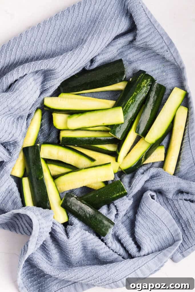 Salted zucchini sticks in a colander to draw out moisture