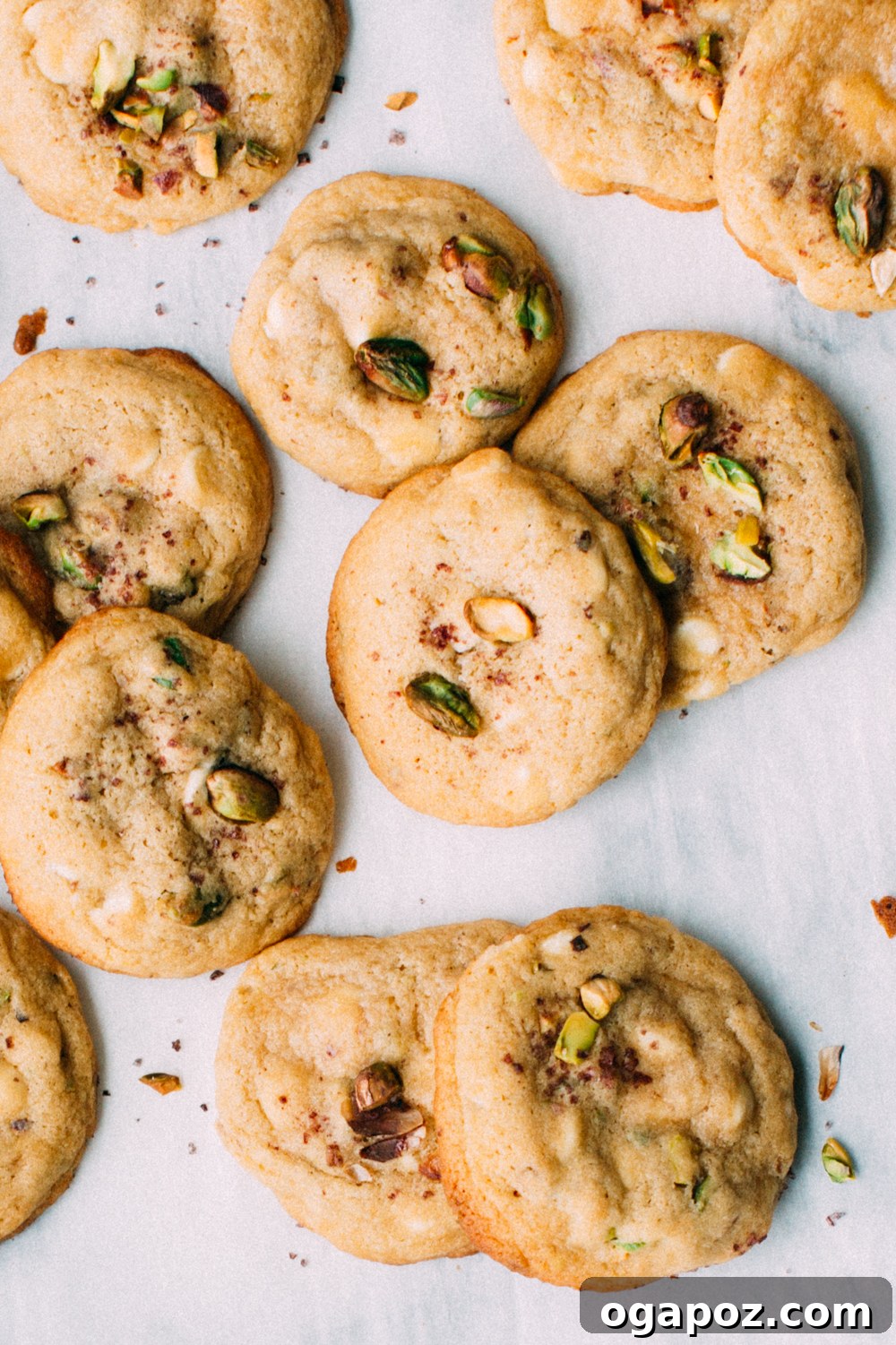 Lemony Pistachio White Chocolate Treasures 6 A hand reaching for a lemon pistachio white chocolate cookie from a plate