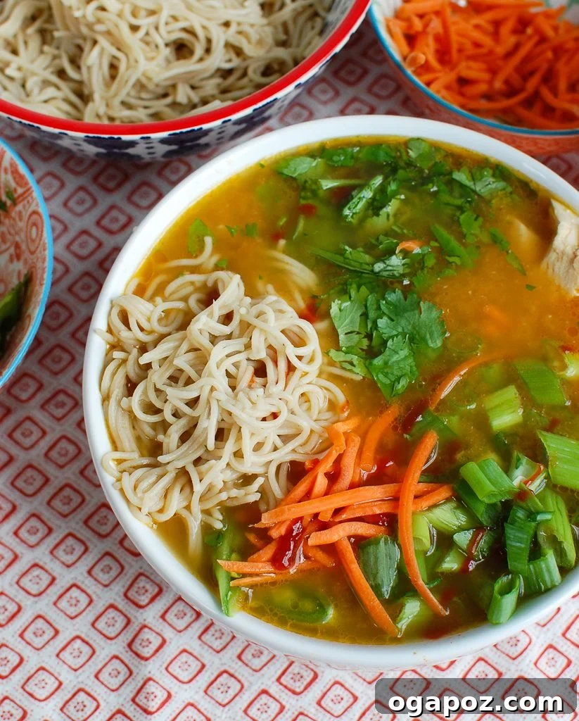 Comforting Asian Chicken Noodle Bowl 2 A vibrant bowl of Asian Chicken Noodle Soup with tender chicken, noodles, carrots, and green onions, garnished with fresh cilantro.
