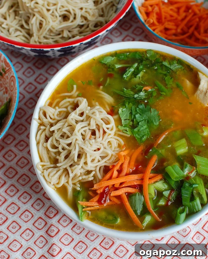 Comforting Asian Chicken Noodle Bowl 4 Close-up of Asian Chicken Noodle Soup, highlighting the cooked rice noodles and tender chicken submerged in the flavorful broth, ready to eat.