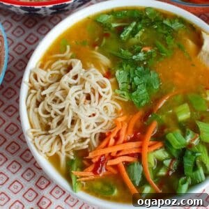 A beautifully presented bowl of Asian Chicken Noodle Soup, ready to be enjoyed with chopsticks.