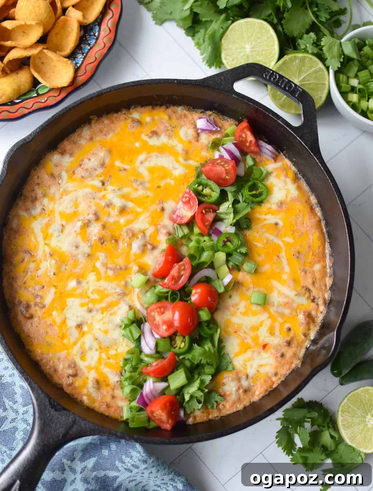 Creamy Beef & Cottage Cheese Queso 4 Cottage cheese beef dip baked in a black cast iron skillet and garnished with diced tomatoes, green onion, cilantro and red onions up above with chips on a plate.
