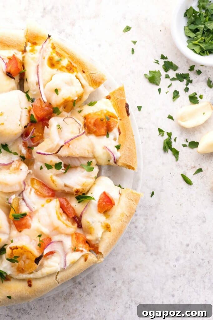 Ocean's Harvest Pizza 6 Half view of delicious seafood pizza on a kitchen countertop, topped with shrimp, scallops, white sauce and a sprinkle of parsley
