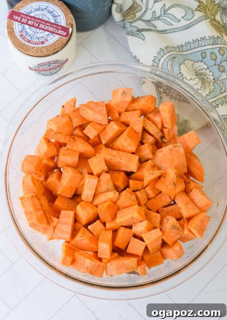 Ground Beef Sweet Potato Cottage Cheese Bowls 8 Diced sweet potatoes tossed with olive oil and spices in a glass bowl, ready for roasting.