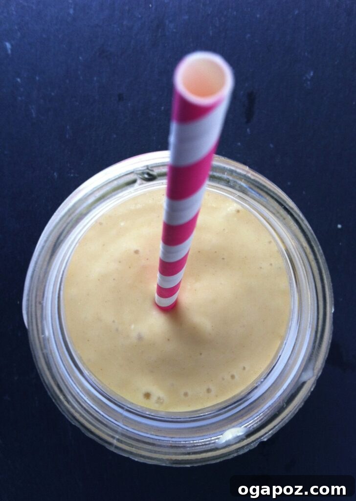 Sunrise Mango Banana Oatmeal Smoothie 3 Close-up view of the creamy texture of Mango Banana Oatmeal Breakfast Smoothie, garnished with a slice of banana.