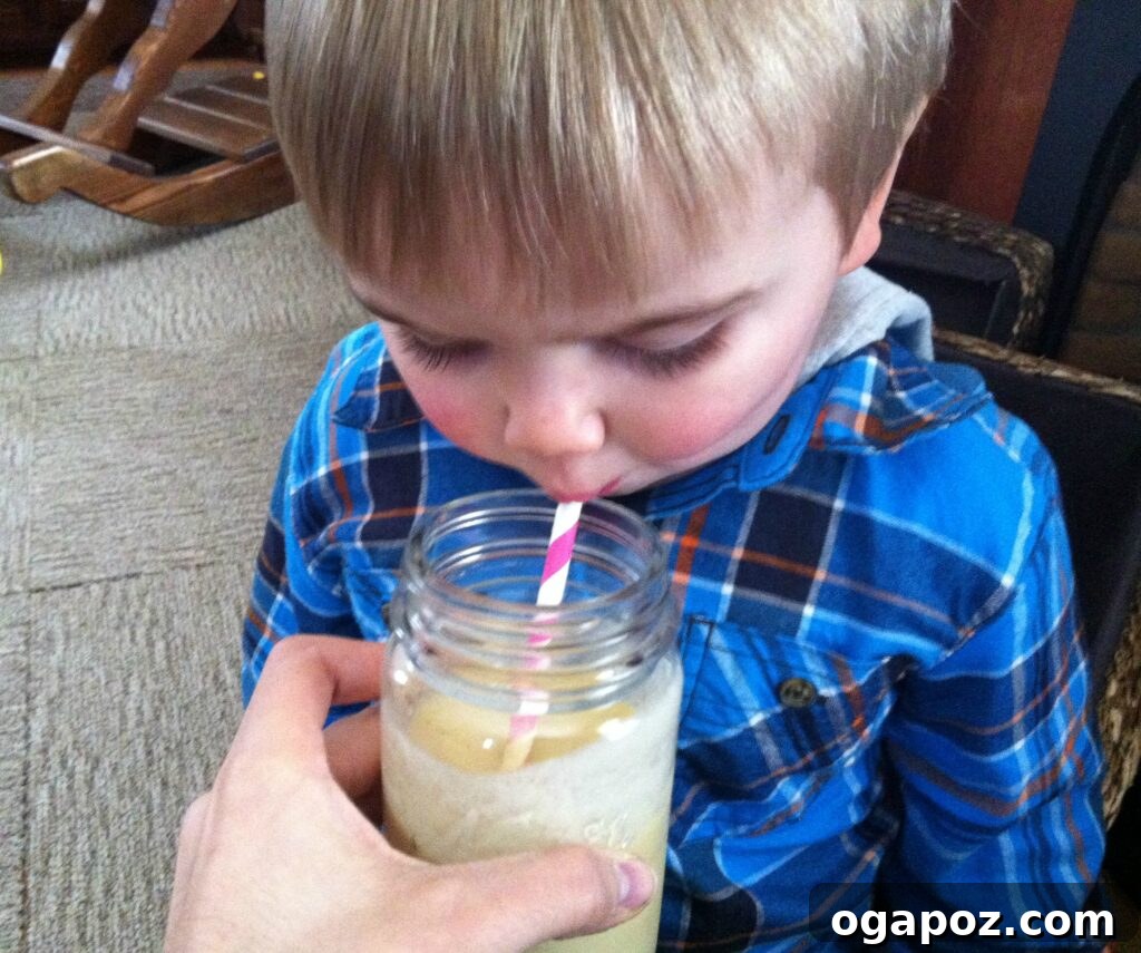Sunrise Mango Banana Oatmeal Smoothie 4 A child happily drinking the Mango Banana Oatmeal Breakfast Smoothie, illustrating its kid-friendly appeal.