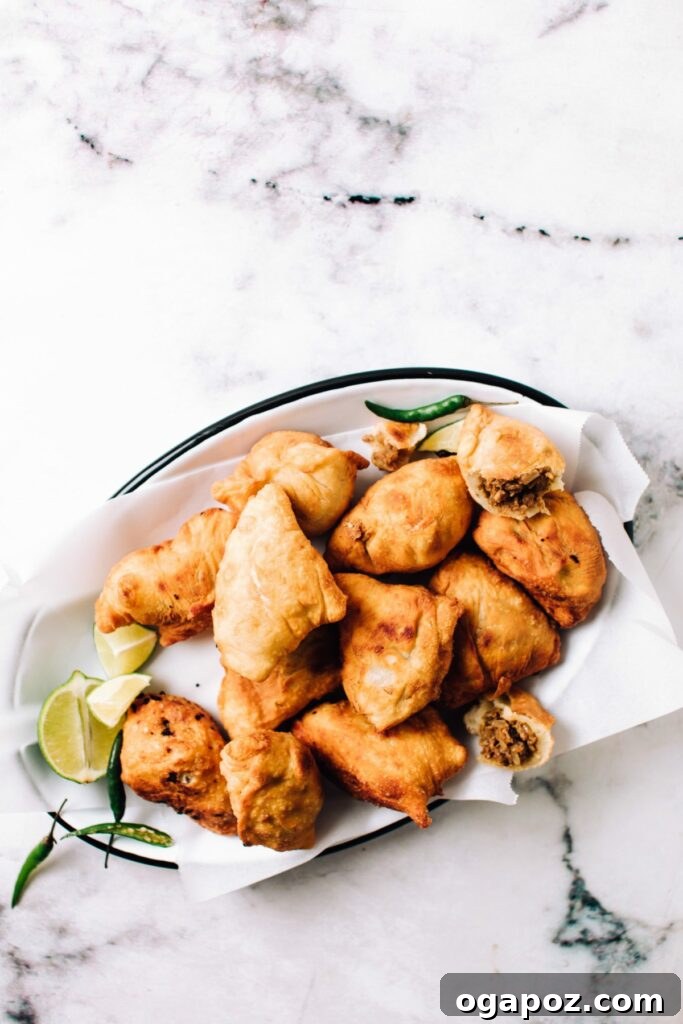 Crispy Chicken Samosas served on a plate with one cut open to reveal the spicy filling.