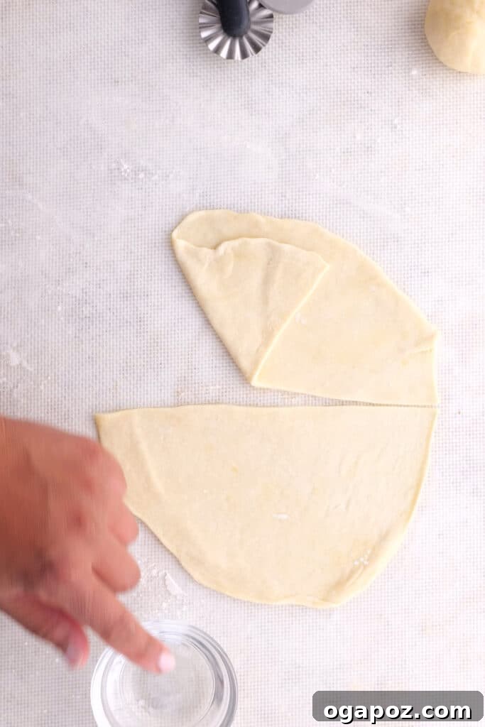 Close-up of dough being cut in half after being flattened for samosas.
