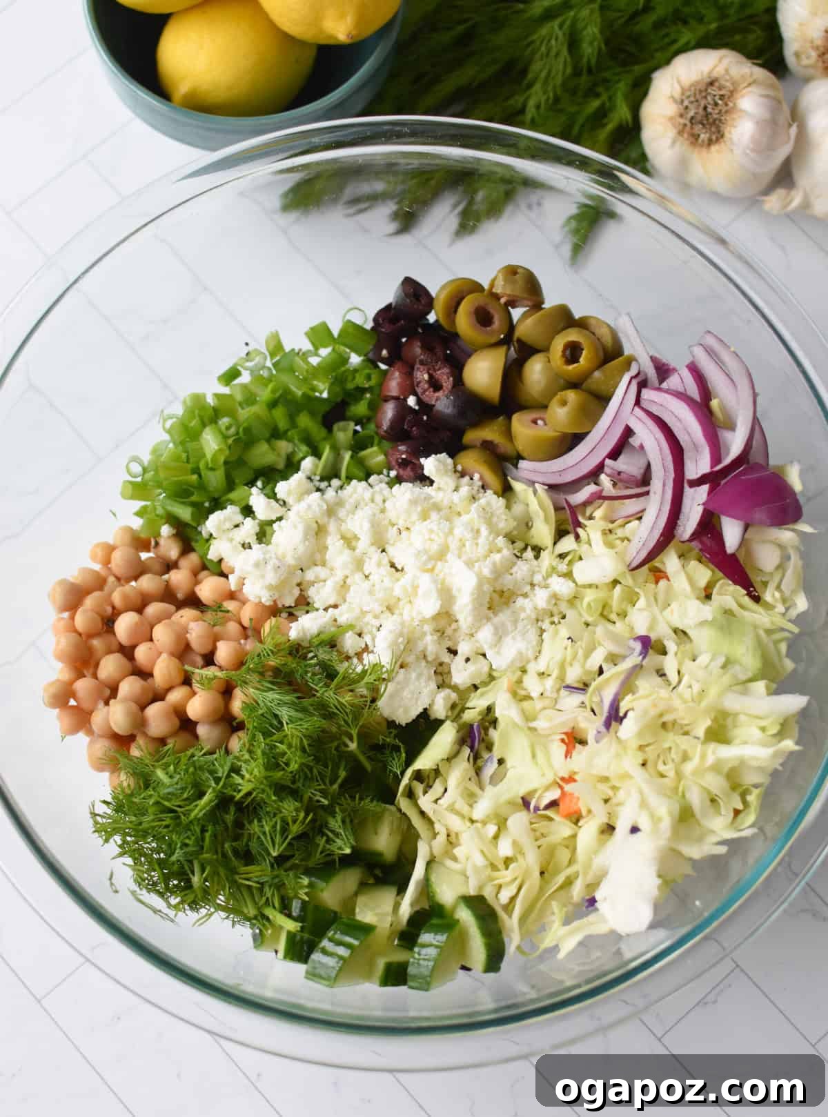 Zesty Greek Cabbage Slaw 8 All Greek Cabbage Salad ingredients, unmixed, in a large clear glass bowl, showcasing their fresh appeal.