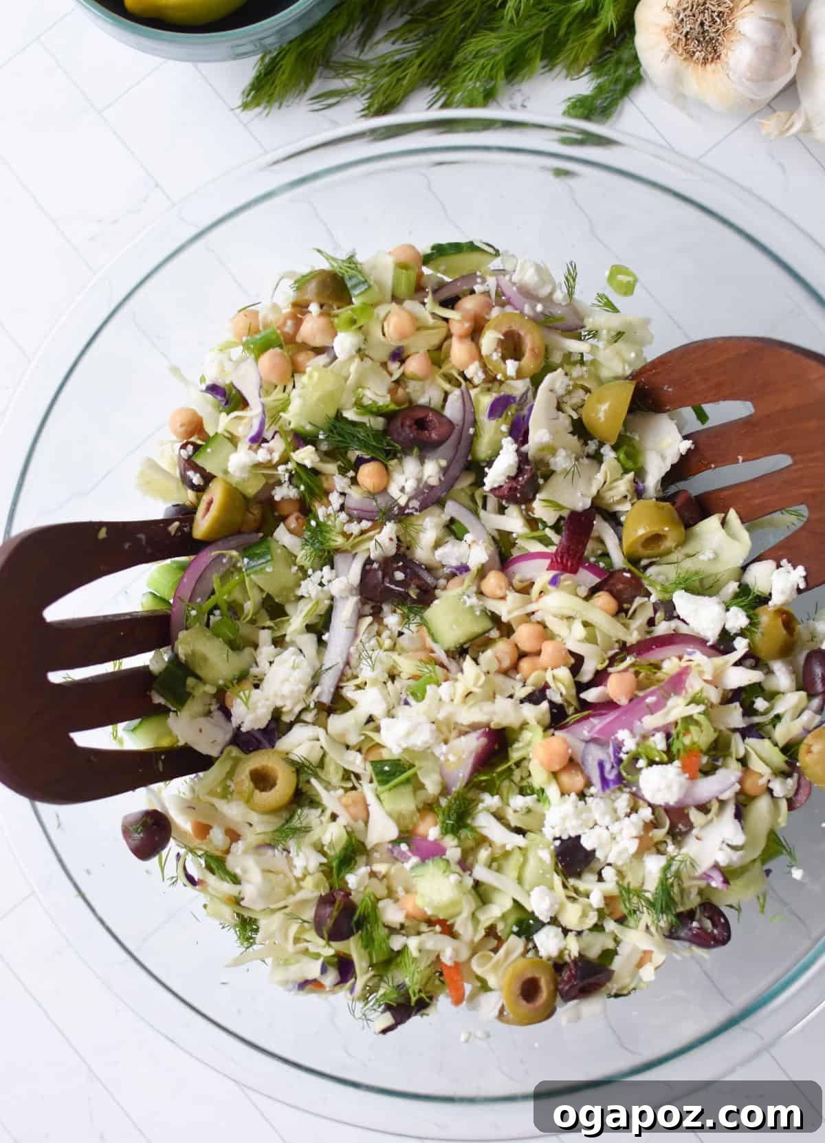 Zesty Greek Cabbage Slaw 9 Greek Cabbage Salad thoroughly mixed in a clear glass bowl, vibrant and ready for dressing.