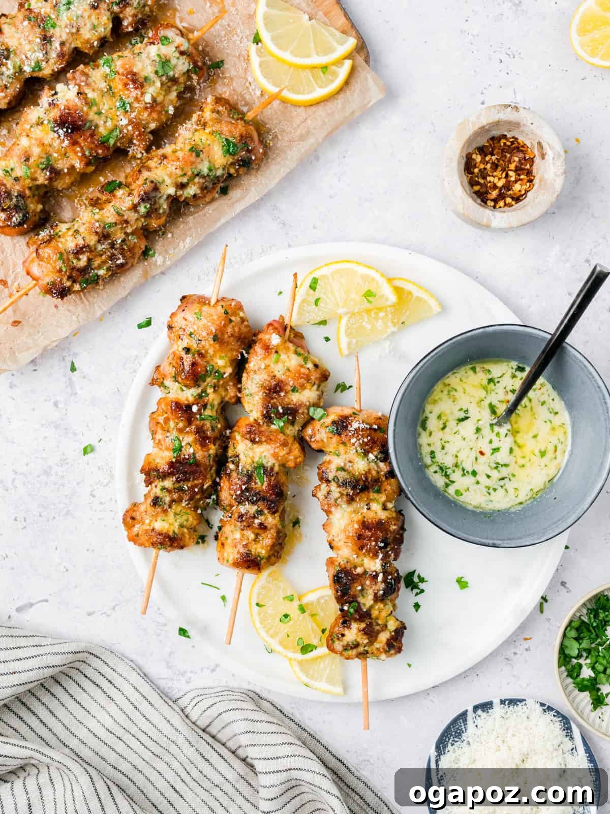 Golden Garlic Parmesan Chicken Skewers 12 Garlic Parmesan Grilled Chicken Skewers garnished with lemon wedges and fresh parsley.