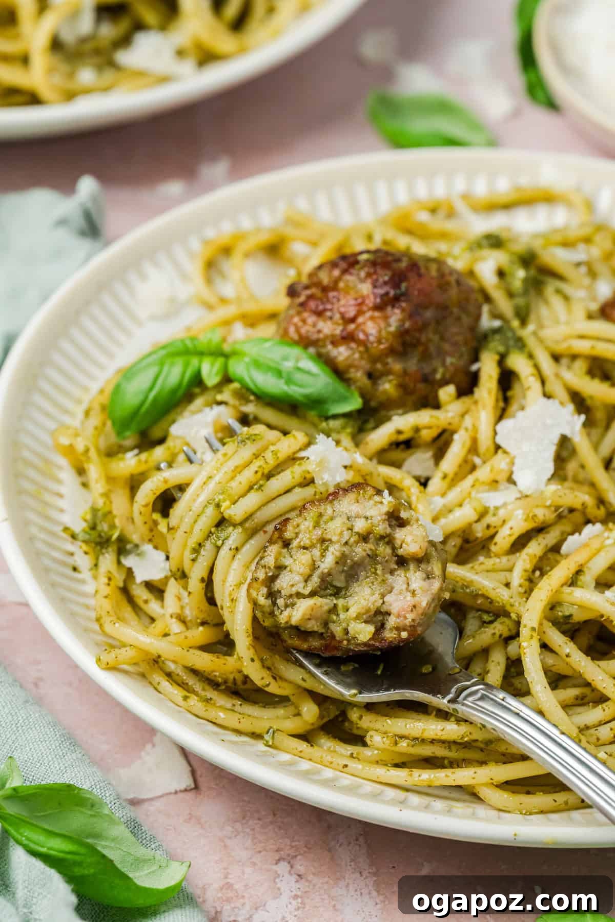 Emerald Pesto Turkey Bites 10 A close-up shot of pesto-coated turkey meatballs on a plate with a fork, highlighting their appealing texture and a rich green sauce.