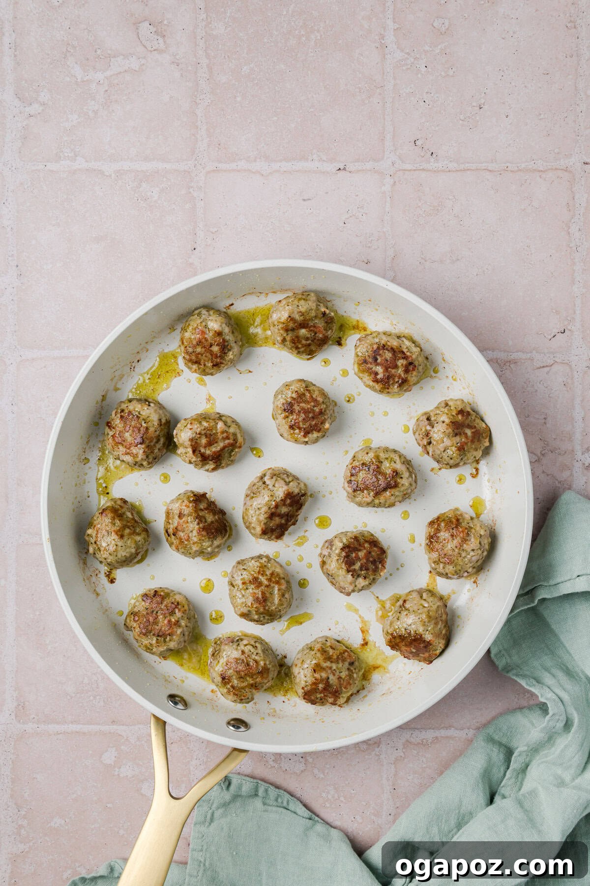 Emerald Pesto Turkey Bites 8 Pesto Turkey Meatballs browning beautifully in a skillet with a vibrant pesto sauce, showcasing a rich golden crust.
