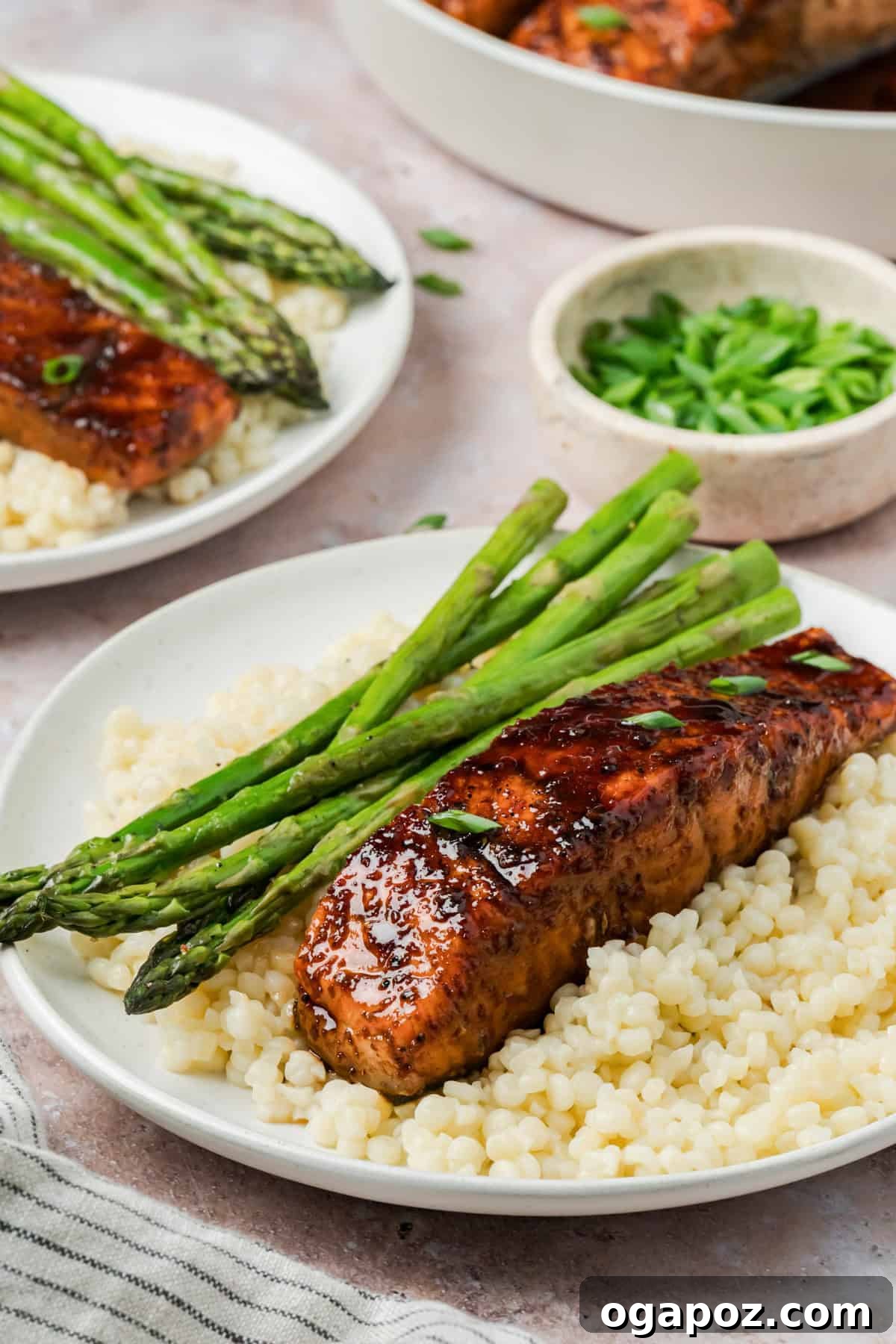 Sticky Bourbon Salmon 2 A beautifully plated Bourbon Glazed Salmon fillet with vibrant green asparagus and a side of couscous on a white plate, ready to be enjoyed.