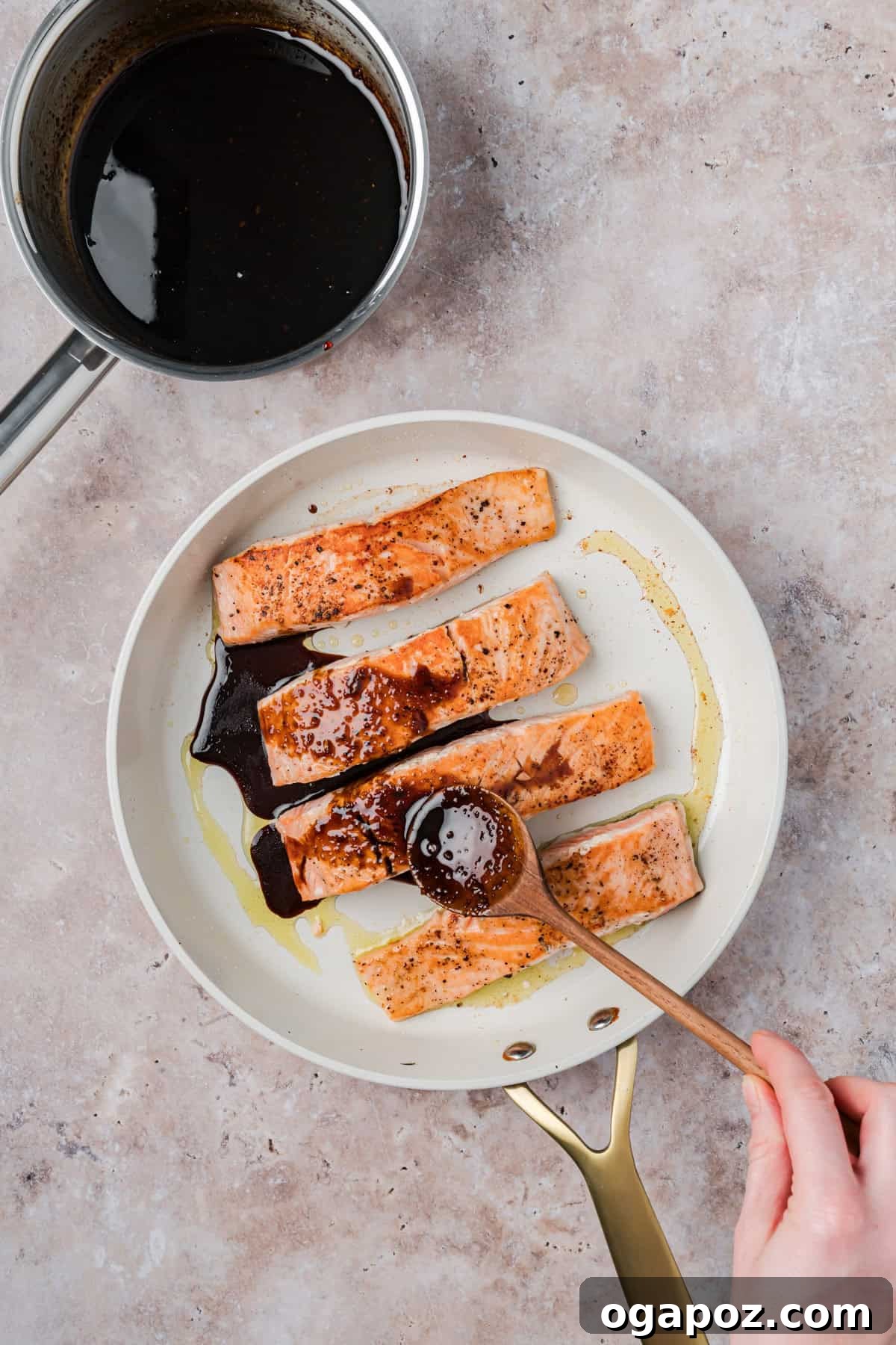 Sticky Bourbon Salmon 11 Bourbon Glazed Salmon fillets cooking in a skillet, with the sticky glaze being spooned over them to caramelize.