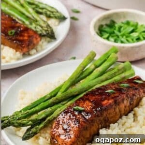 Bourbon Glazed Salmon on a white plate with asparagus and lemon