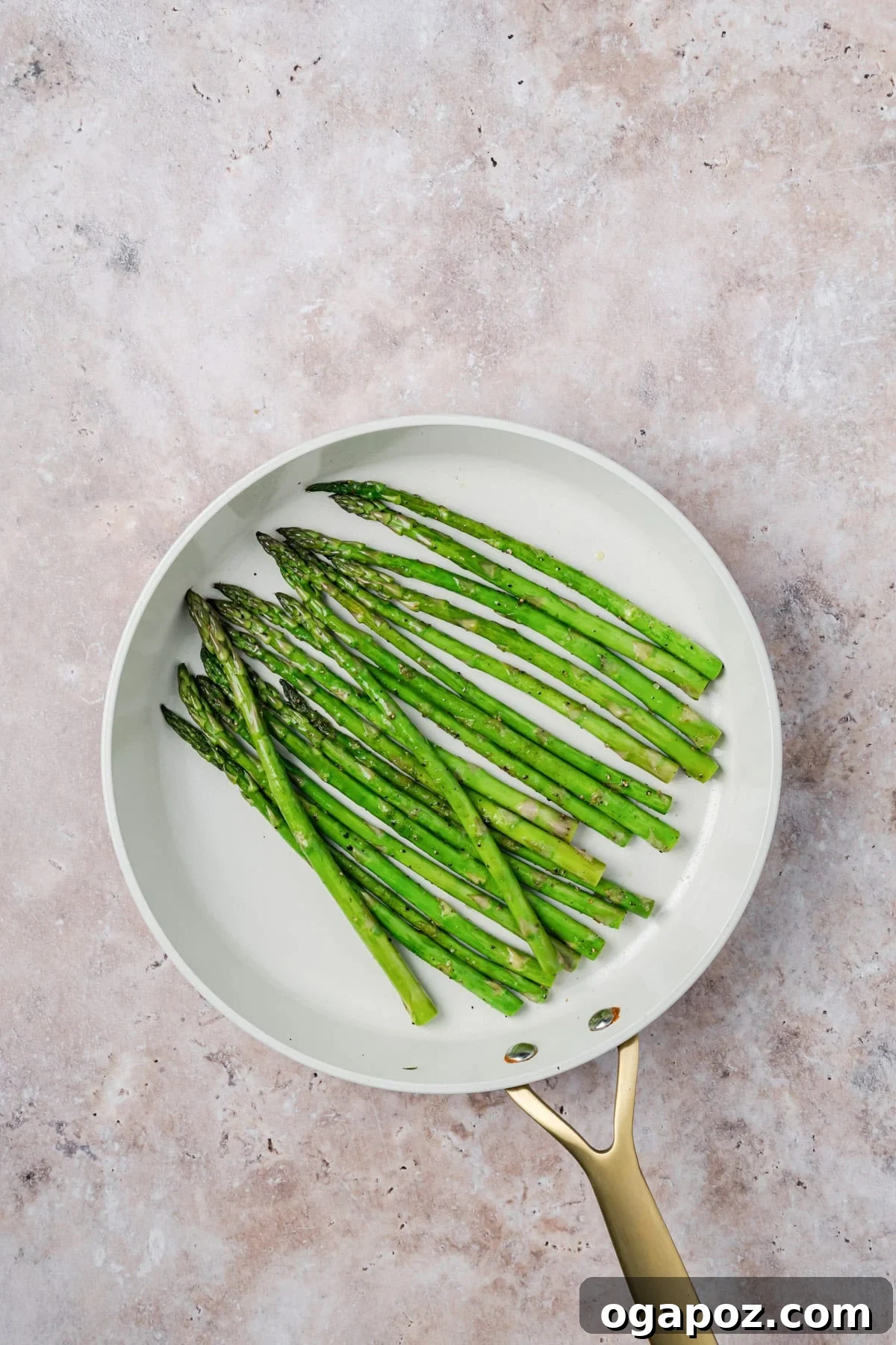 Sticky Bourbon Salmon 9 Fresh asparagus spears cooking in a large skillet with olive oil, showing them becoming bright green and slightly tender.