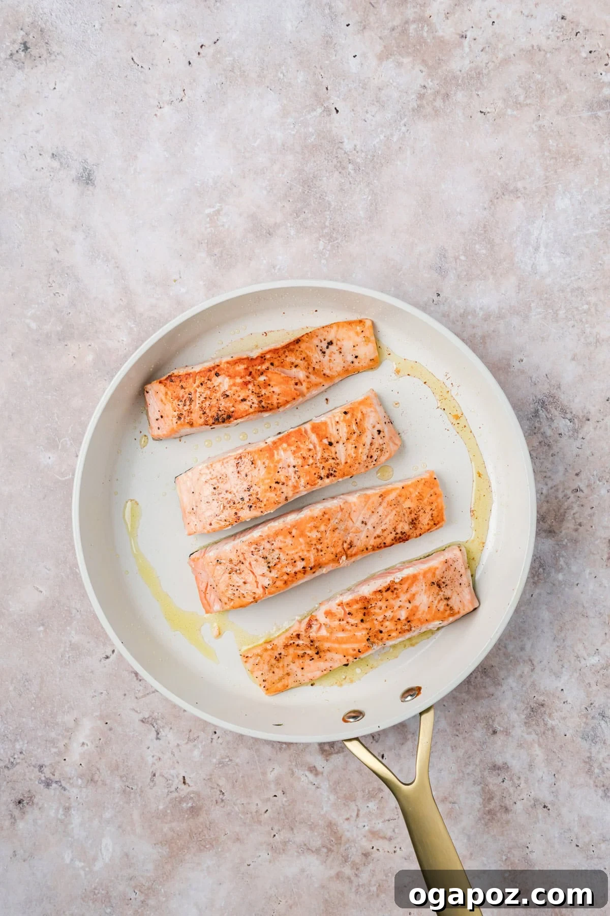 Sticky Bourbon Salmon 10 Salmon fillets being pan-seared in a hot skillet, skin-side up, with a golden crust forming.