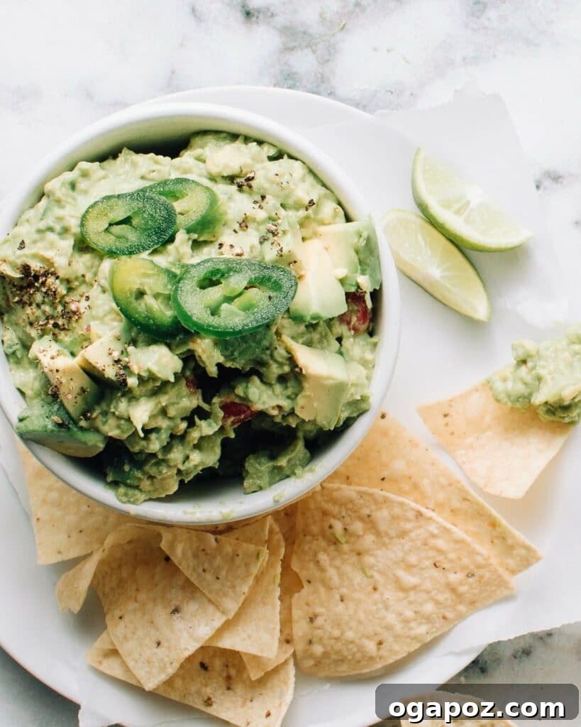 Authentic Mexican guacamole in a bowl, garnished with fresh cilantro and jalapeños