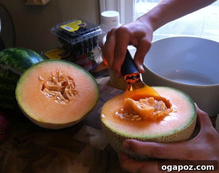 Refreshing Fruit Medley with Zesty Honey-Yogurt Dressing 8 A halved cantaloupe on a cutting board, revealing its vibrant orange flesh and central cavity with seeds, ready for deseeding.