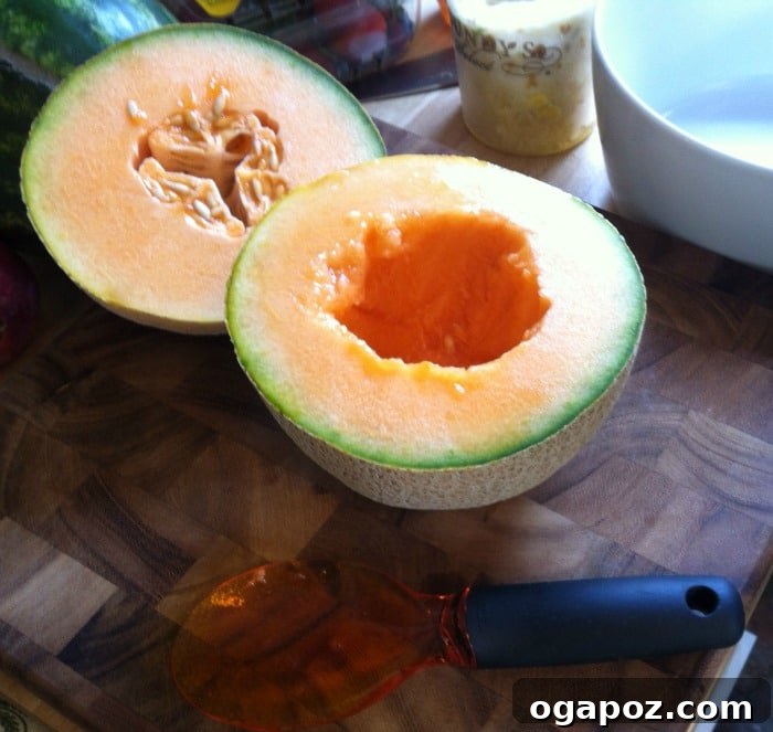 Refreshing Fruit Medley with Zesty Honey-Yogurt Dressing 9 Close-up of a fruit scoop being used to efficiently remove seeds from a cantaloupe, demonstrating the ease and effectiveness of the tool.
