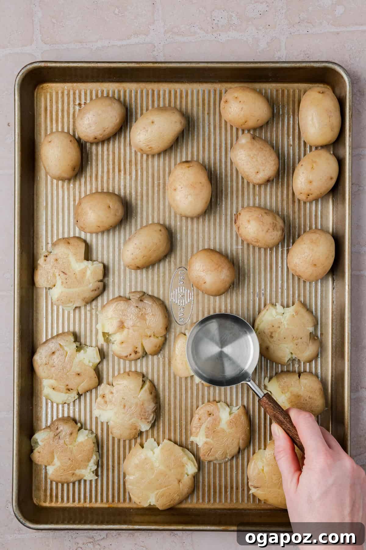 Crispy Garlic Parmesan Smashed Potatoes 10 Potatoes being gently smashed on a baking sheet.
