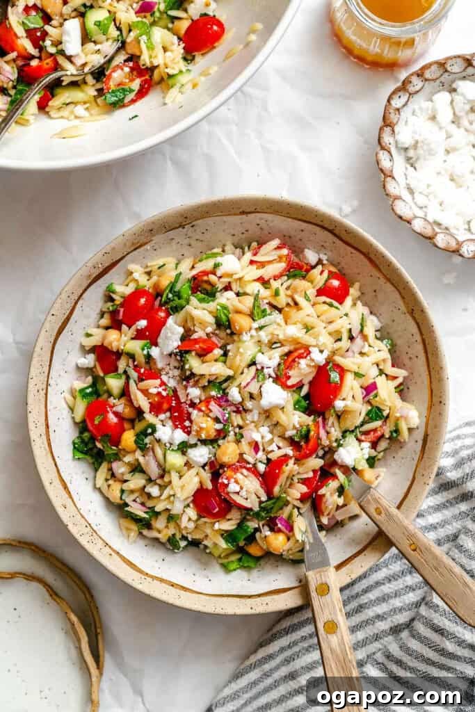 Bright Summer Orzo Salad 5 A refreshing bowl of Summer Orzo Pasta Salad with a fork and spoon, inviting a taste.