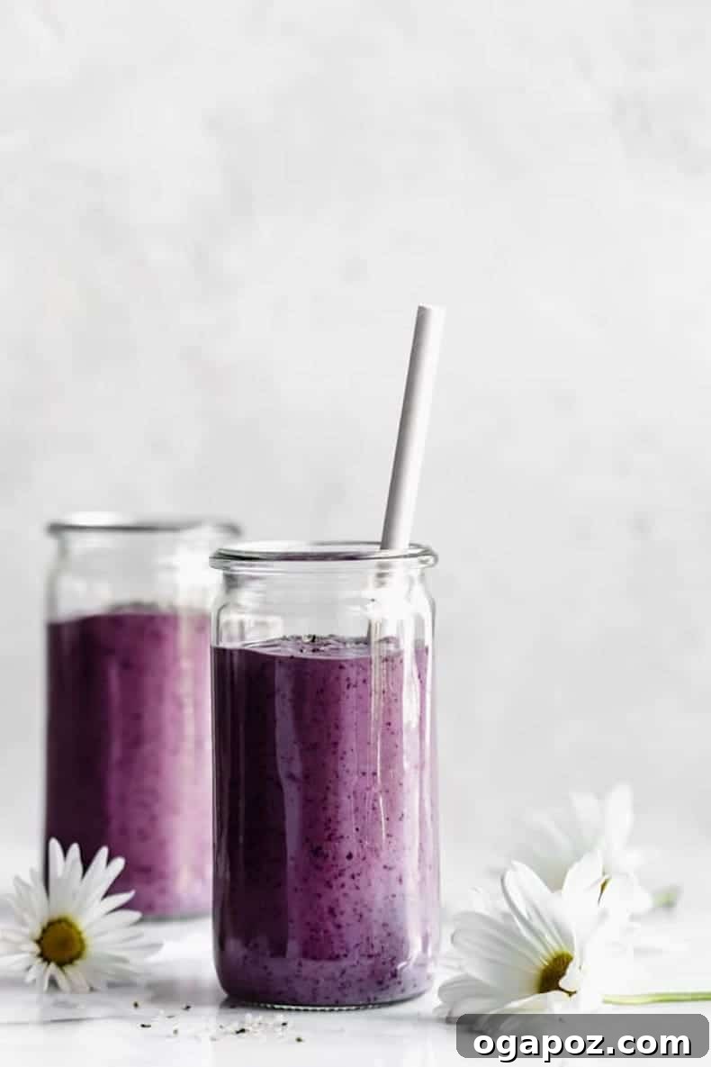 Transform Your Health: 25+ Irresistible Smoothie Creations 18 Blueberry avocado smoothie on a marble backdrop with a daisy on the table