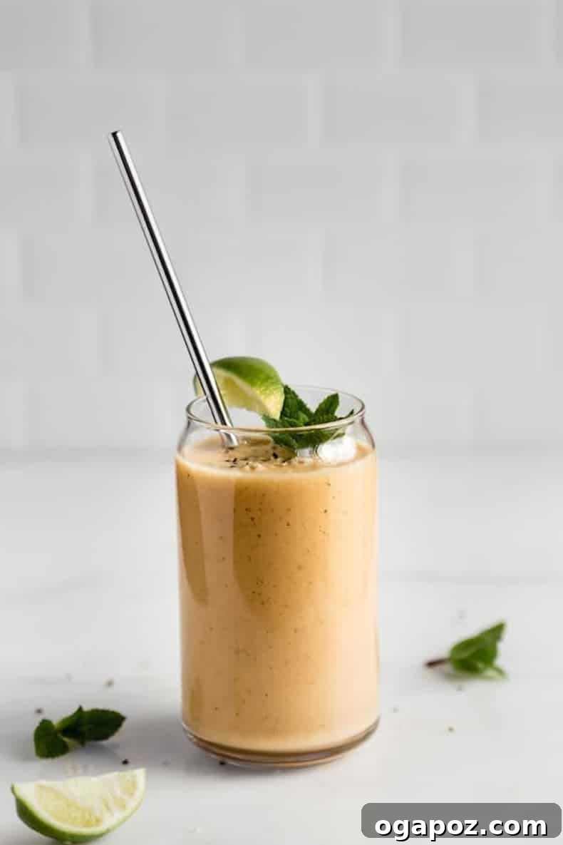 Transform Your Health: 25+ Irresistible Smoothie Creations 20 Orange smoothie in a glass with a straw and mint leaf on a table