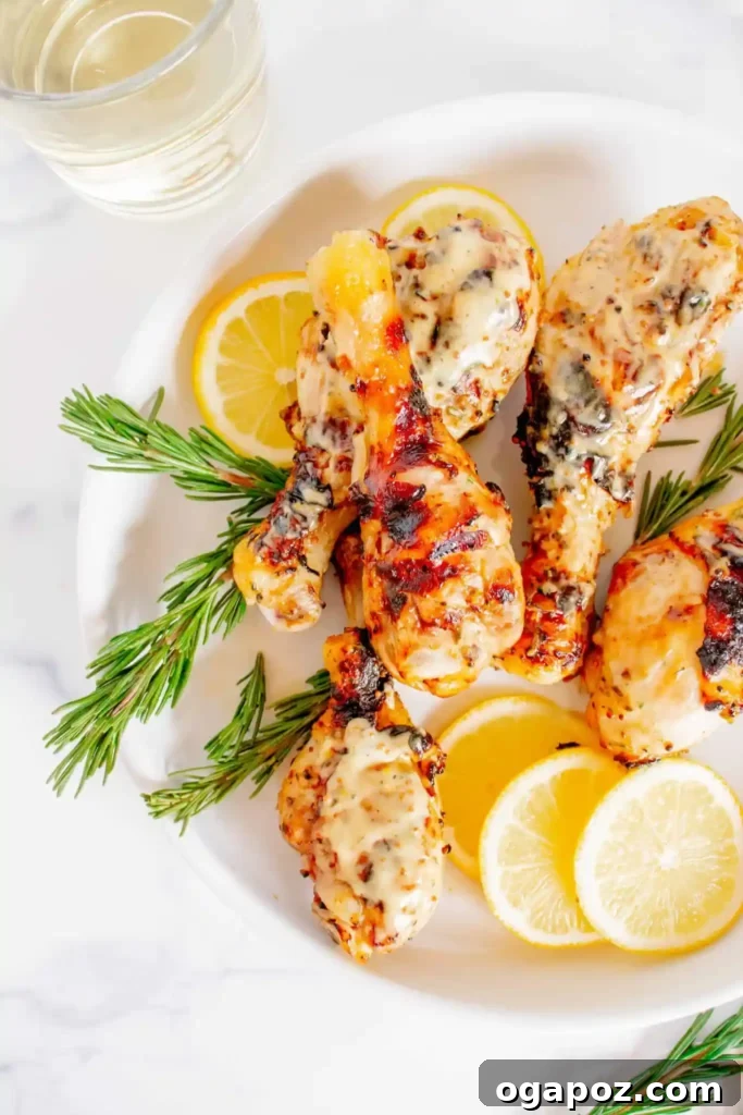 41 Delicious Chicken Drumstick Recipes: Simple and Super Juicy 16 Grilled Honey Mustard Chicken Drumsticks on a white plate with sliced lemon and rosemary