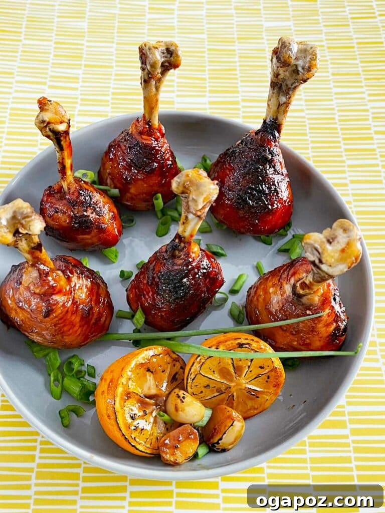 41 Delicious Chicken Drumstick Recipes: Simple and Super Juicy 23 Lollipop Chicken Drumsticks served on a plate with lime wedges and scallions