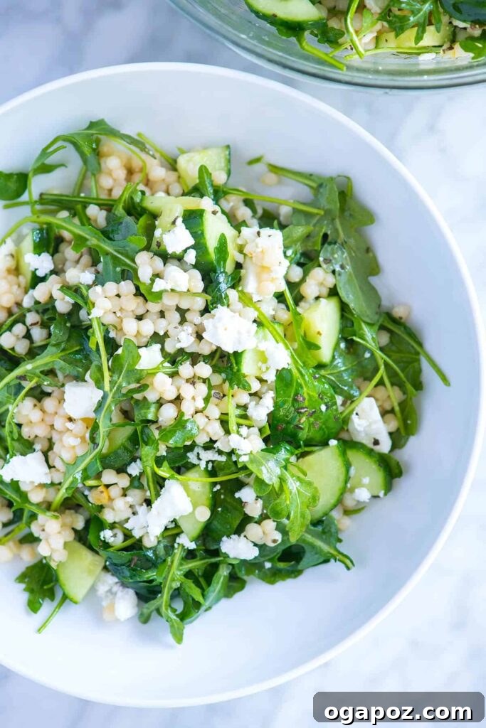 9+ Phenomenal Israeli Couscous Recipes You Must Try 11 A refreshing Lemony Arugula Salad featuring Israeli couscous, crumbled feta, and crisp cucumber, artfully arranged.