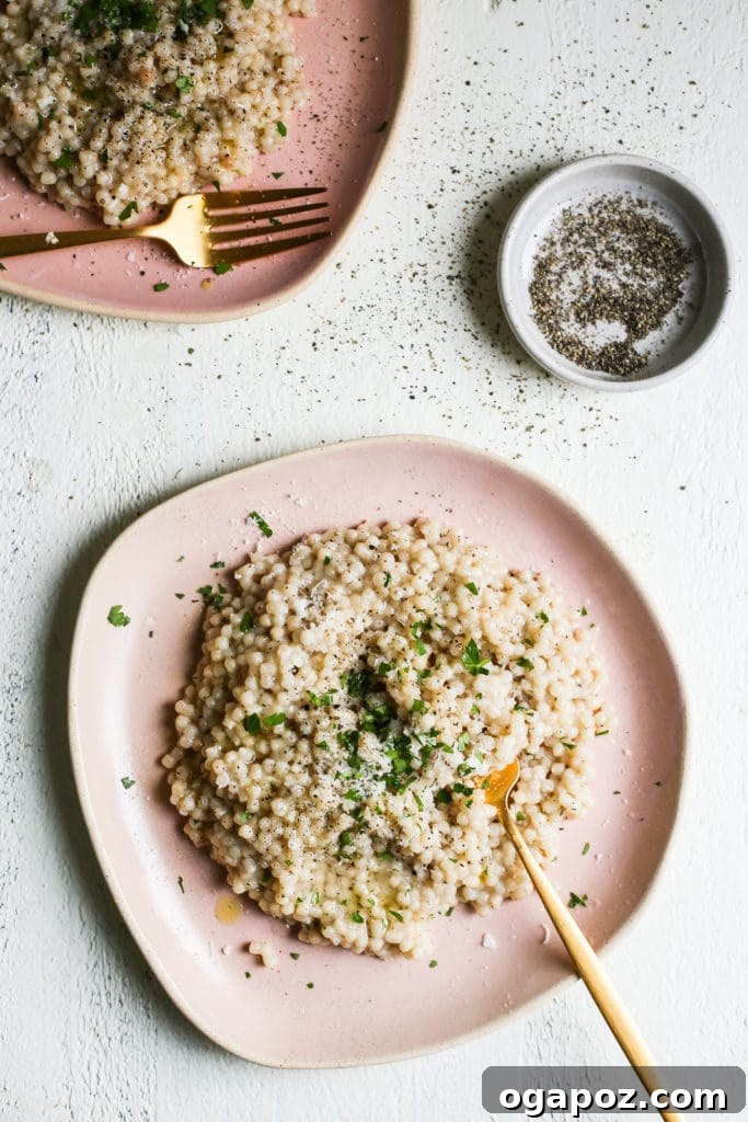 9+ Phenomenal Israeli Couscous Recipes You Must Try 4 A plate of creamy Israeli couscous richly garnished with fresh pepper and aromatic herbs, presenting a gourmet and comforting dish.