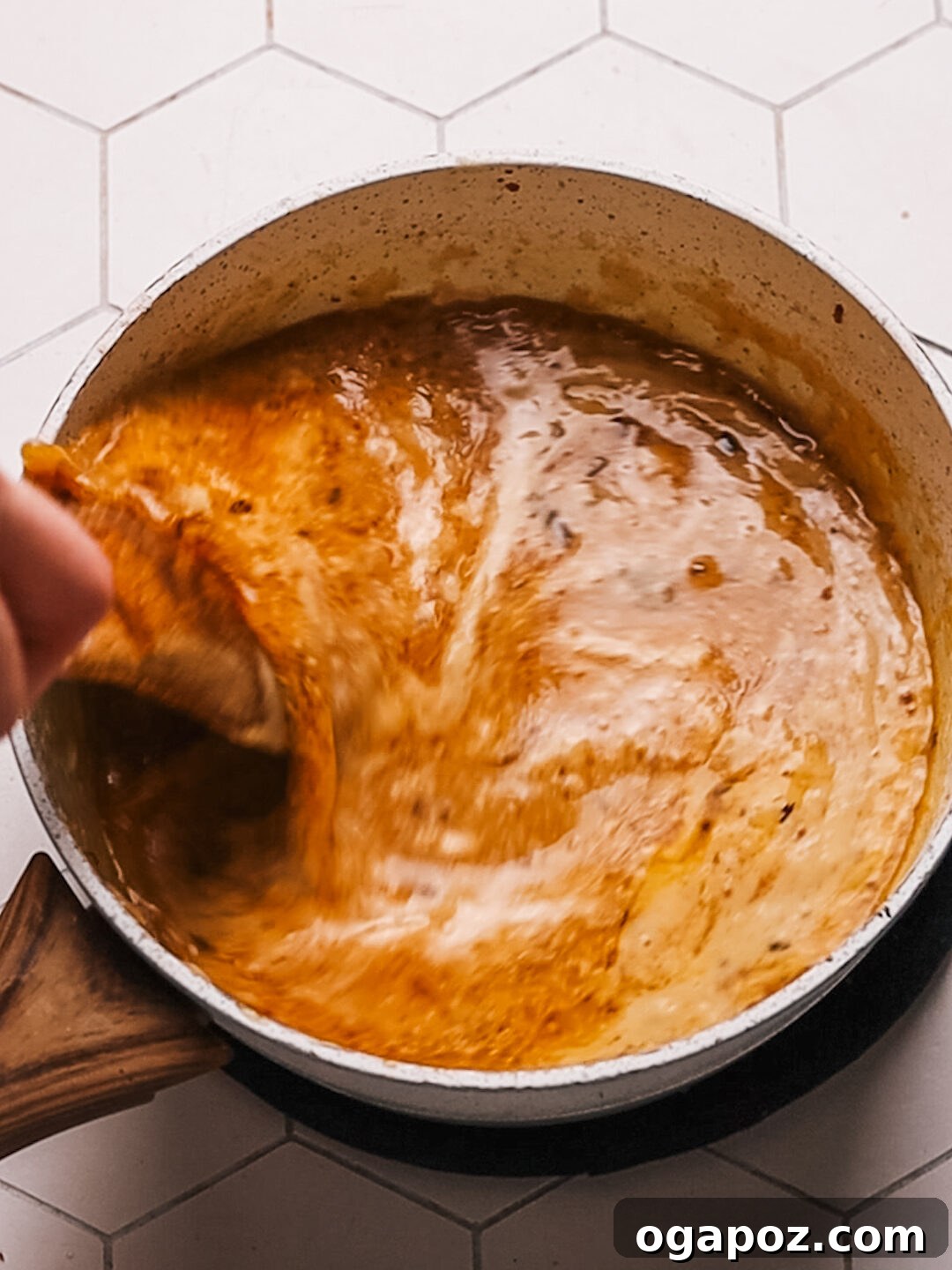 Classic Homemade Pork Gravy 10 A close-up of a chef mixing the roast pork loin pan sauce in a bowl with a whisk.