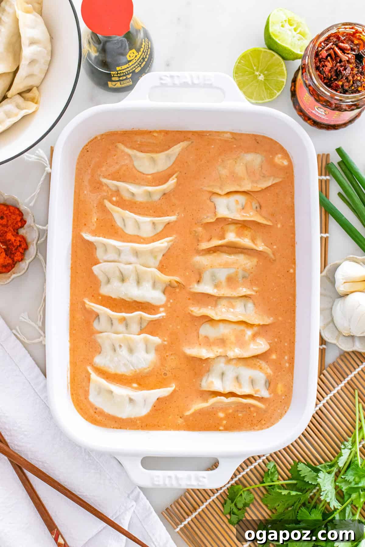 Savory One Pan Dumpling Bake 9 Image of frozen dumplings neatly arranged in the coconut curry sauce within the baking pan, ready for the oven.