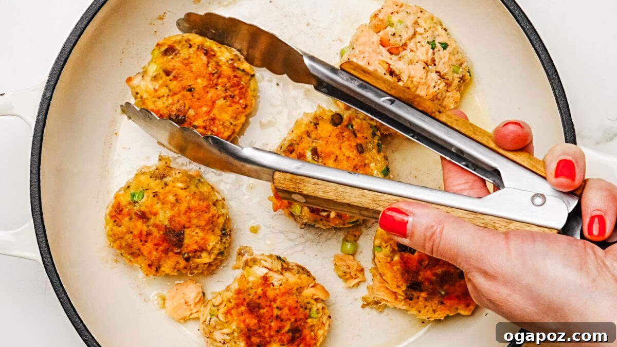 Golden Salmon Cakes 6 Frying six salmon patties in a skillet with oil.