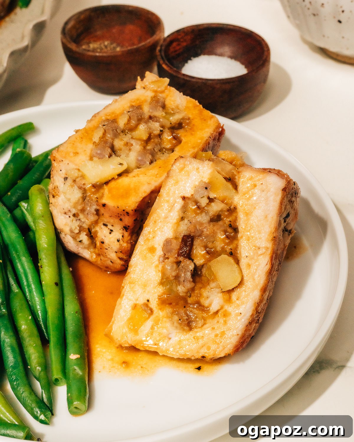 Signature Stuffed Pork Chops with an Unforgettable Pan Sauce 10 A finished stuffed pork chop, beautifully seared and cut open to showcase the delicious, moist sausage and apple stuffing inside, drizzled with pan sauce.