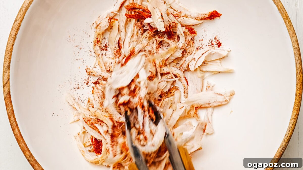 Ultimate Chicken Quesadilla 5 Shredded chicken being tossed with chili powder and salt in a bowl for seasoning.